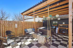 View of patio / terrace featuring a hot tub, an outdoor hangout area, and fence