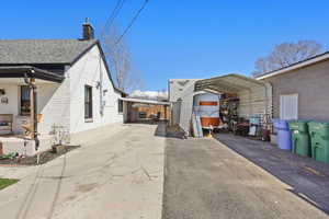 View of home's exterior featuring aphalt driveway, a detached carport, a chimney, and brick siding