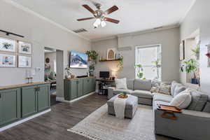 Living area featuring dark wood-type flooring, crown molding, ceiling fan, and visible vents