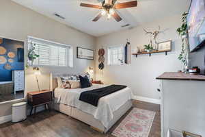 Bedroom with dark wood-type flooring, baseboards, and visible vents