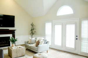 Living room featuring light colored carpet, high vaulted ceiling, a fireplace, and visible vents