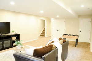 Living area featuring light carpet, recessed lighting, baseboards, and stairway