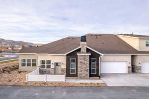 View of front of home featuring stone siding, driveway, fence, stucco siding, and a mountain view
