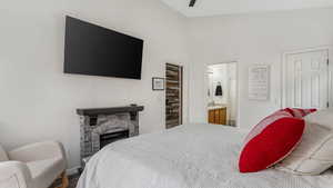 Bedroom featuring a stone fireplace, a sink, ensuite bath, and baseboards