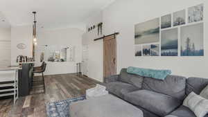Living room with a barn door, dark wood-style floors, and high vaulted ceiling