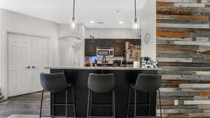 Kitchen featuring stainless steel appliances, a kitchen bar, arched walkways, light countertops, and decorative light fixtures