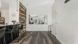 Corridor with dark wood finished floors and high vaulted ceiling