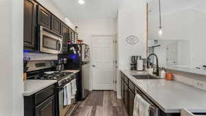 Kitchen with stainless steel appliances, a sink, dark wood-style flooring, light stone countertops, and a peninsula