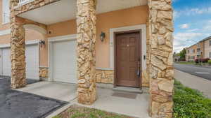 Property entrance featuring stone siding, stucco siding, and a garage