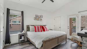 Bedroom with vaulted ceiling, wood finished floors, access to exterior, and ceiling fan