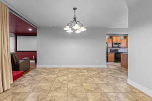 Unfurnished dining area with a chandelier and baseboards