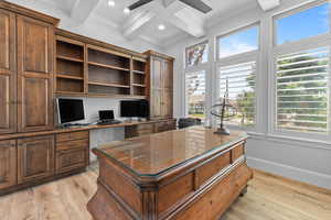 Office space with beam ceiling, light wood-style floors, crown molding, built in desk, and recessed lighting