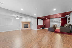 Living room with a ceiling fan, wood finished floors, a glass covered fireplace, recessed lighting, and baseboards