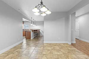 Unfurnished dining area featuring a chandelier and baseboards