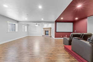 Cinema room with recessed lighting, wood finished floors, baseboards, ceiling fan, and a glass covered fireplace