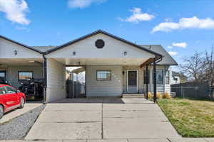 View of front of property featuring a gate, fence, concrete driveway, a front yard, and a carport