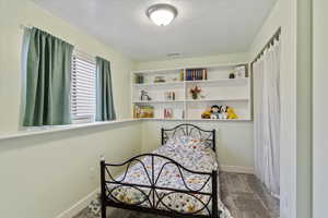 Carpeted bedroom featuring baseboards, a textured ceiling, and visible vents