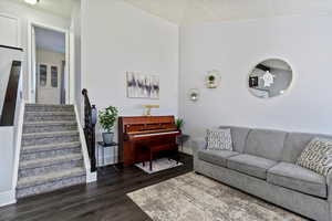 Living room with dark wood-type flooring, baseboards, and stairs