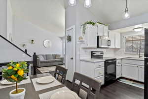 Kitchen with light countertops, a sink, lofted ceiling, stainless steel microwave, and black / electric stove