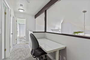 Office with beam ceiling, baseboards, light colored carpet, and a textured ceiling