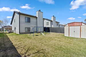 Rear view of house with a playground, a shed, an outbuilding, and fully fenced yard