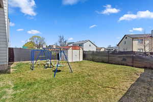 View of back yard featuring a shed, a fully fenced yard, a residential view, and a playground