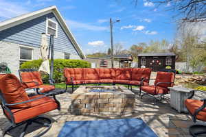 View of patio featuring a storage unit, an outdoor structure, and an outdoor living space with a fire pit