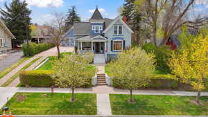 Victorian-style house with a porch, roof with shingles, stairs, and a front yard