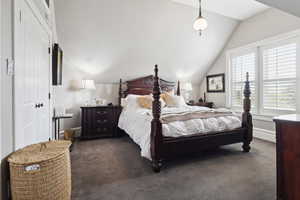 Bedroom with dark carpet, a closet, lofted ceiling, and baseboards