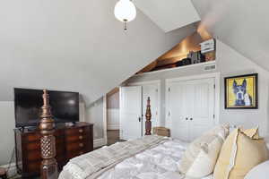 Carpeted bedroom featuring visible vents and vaulted ceiling