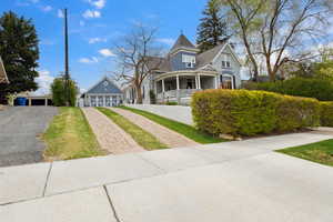 Victorian house with a porch, a detached garage, and aphalt driveway