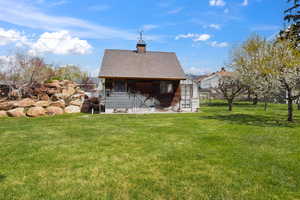 Back of house with roof with shingles, an outbuilding, and a lawn