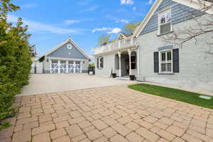 View of front of home featuring brick siding, a balcony, an outbuilding, and driveway