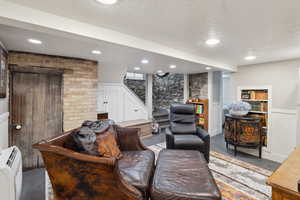 Living area featuring stairs, a decorative wall, a wainscoted wall, finished concrete flooring, and a textured ceiling
