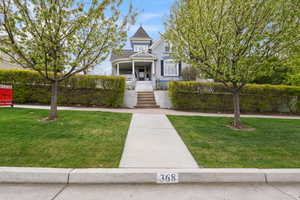 Victorian house with covered porch, a front yard, and stairs