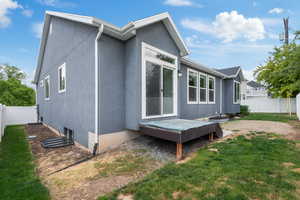 Back of house with stucco siding and a wooden deck