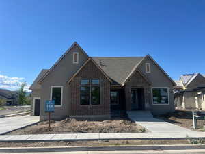Craftsman-style house featuring concrete driveway, brick siding, a shingled roof, and a garage
