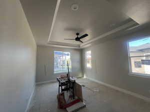 Unfurnished room featuring baseboards, a ceiling fan, and a tray ceiling