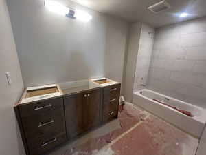 Bathroom with visible vents, tub / shower combination, and vanity