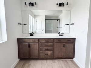 Bathroom with wood finished floors, double vanity, and a sink