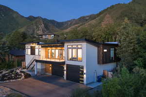 Contemporary house with stairs, a mountain view, a garage, driveway, and a balcony