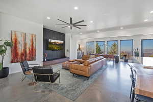 Living room with concrete flooring, ceiling fan, baseboards, and recessed lighting