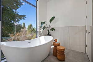 Bathroom featuring concrete floors and a freestanding tub