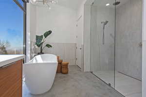 Bathroom featuring a freestanding bath, a notable chandelier, concrete flooring, and a marble finish shower