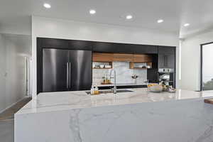 Kitchen with tasteful backsplash, a large island, modern cabinets, appliances with stainless steel finishes, and dark cabinets