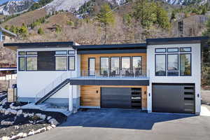 Modern home with a mountain view, driveway, a garage, and stairway