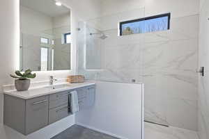 Bathroom with vanity and a marble finish shower