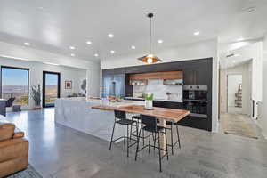Kitchen featuring light countertops, tasteful backsplash, concrete floors, modern cabinets, and stainless steel appliances