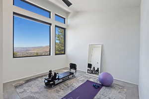 Workout area with baseboards, ceiling fan, a high ceiling, and a healthy amount of sunlight