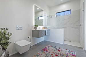 Full bath with toilet, vanity, a marble finish shower, concrete floors, and baseboards